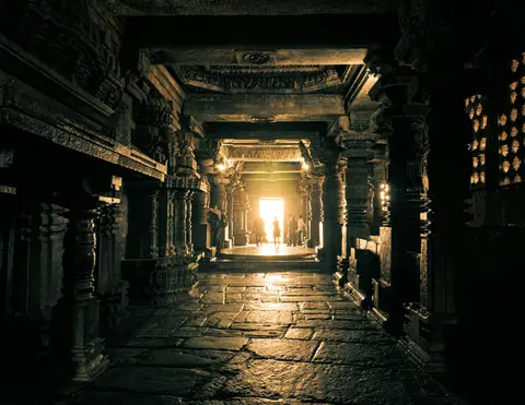 Sunlight streams into ancient stone temple corridor.