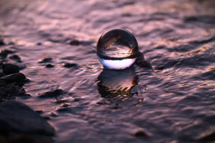 Glaskugel am Ufer mit violettem Licht — Sinnbild technologischer Zukunftsversprechen