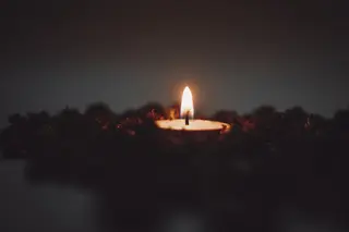 Einzelne Kerzenflamme in der Dunkelheit, kontemplative Stimmung