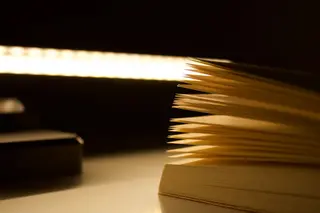 Aufgeschlagenes Buch mit beleuchteten Seiten in warmem Daemmerlicht