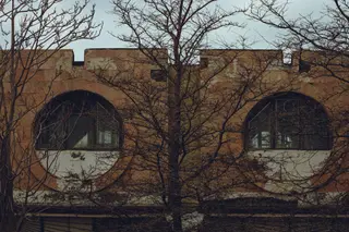 Altes Backsteingebäude mit runden Fenstern und kahlen Baeumen