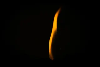 Einzelne Flamme in der Dunkelheit, prometheisches Feuer