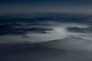 Wolkenmeer ueber Berggipfeln im Morgenlicht aus der Vogelperspektive