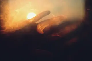 Hand haelt Sonnenlicht mit goldenem, aetherischem Effekt