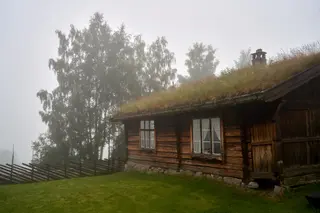 Traditionelles norwegisches Holzhaus mit Grasdach im Morgennebel