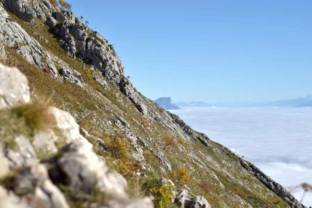 Rocky mountain slope above a sea of clouds under a clear blue sky
